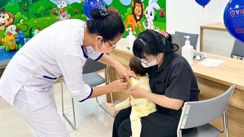 điều dưỡng viên đang tiêm vắc xin cho trẻ